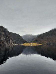 Norsk fjord med høje bjerge, stille vand og smuk natur omgivet af dramatiske fjeldlandskaber.