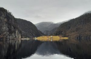 Norsk fjord omgivet af bjerge og spejlblankt vand med dramatisk natur og udsigt til fjelde i Norge.