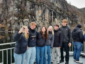 Studerende på bådtur i norske fjorde med klipper, natur og fokus på fællesskab og oplevelser på studietur.