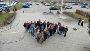 Gruppe af studerende samlet udenfor skole og uddannelsesinstitution med fokus på fællesskab og studiemiljø.