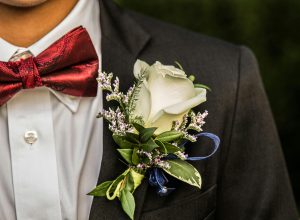 Hvid rose som boutonniere på sort jakkesæt med rød butterfly til gallafest, bryllup eller formel begivenhed.